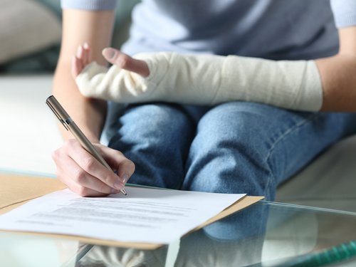 Person mit Gips um den Arm unterschriebt Kündigung